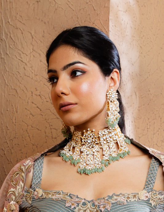 Featuring an 18kt gold plated 92.5 silver Vellore polki heavy choker set with green carved drops & fresh water pearls.