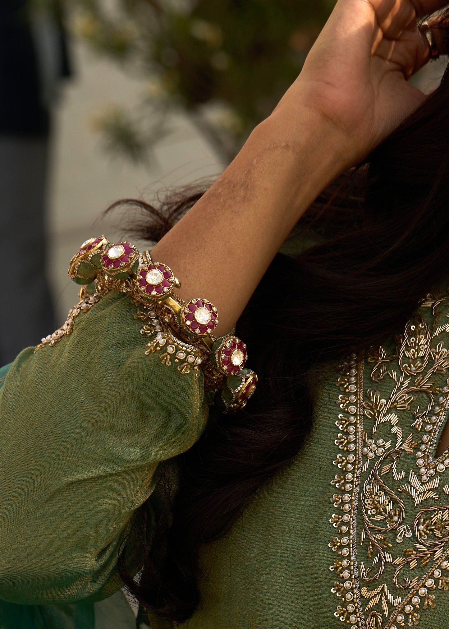 Close-up of a hand wearing a decorative bracelet on a person in traditional attire.