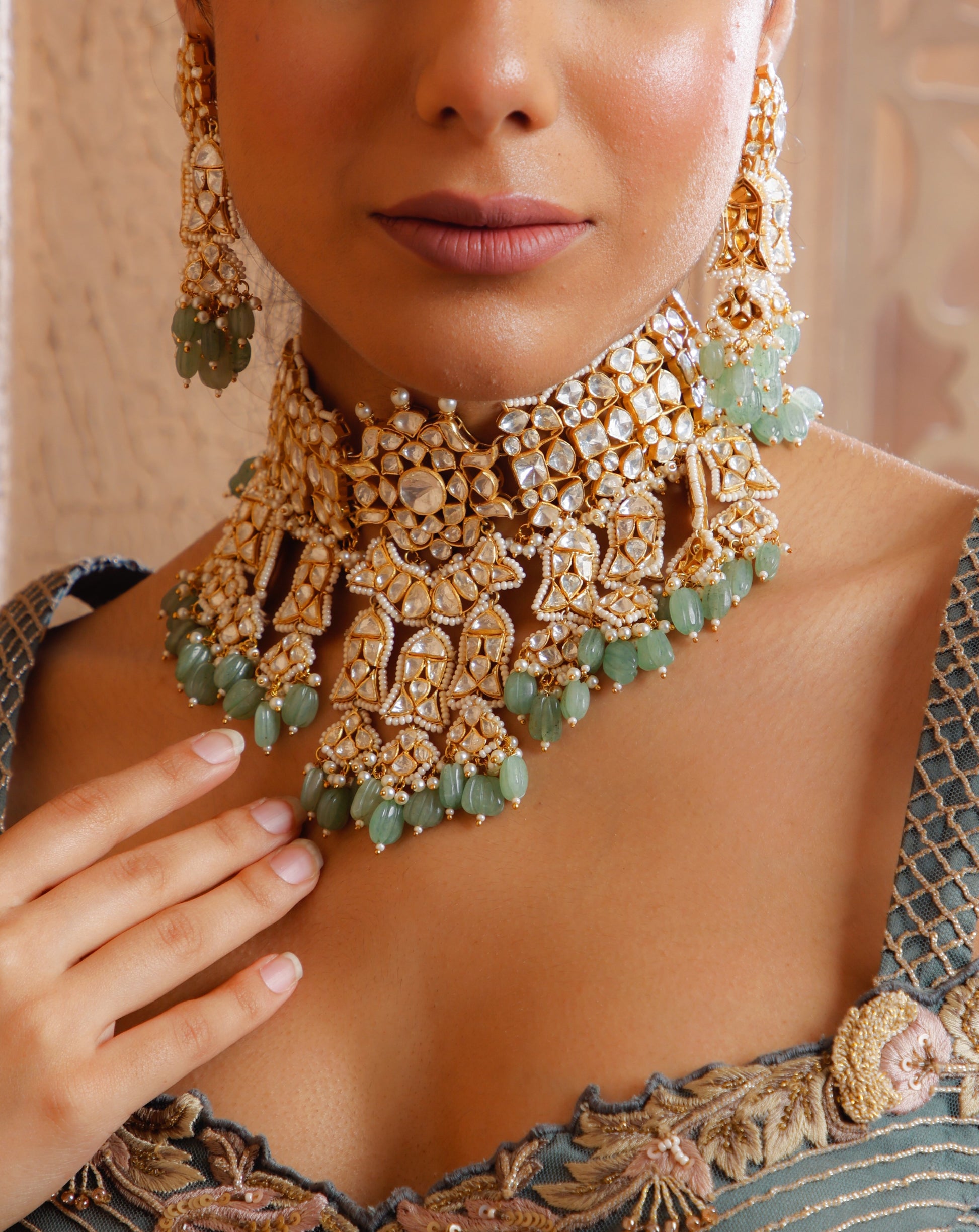 Featuring an 18kt gold plated 92.5 silver Vellore polki heavy choker set with green carved drops & fresh water pearls.